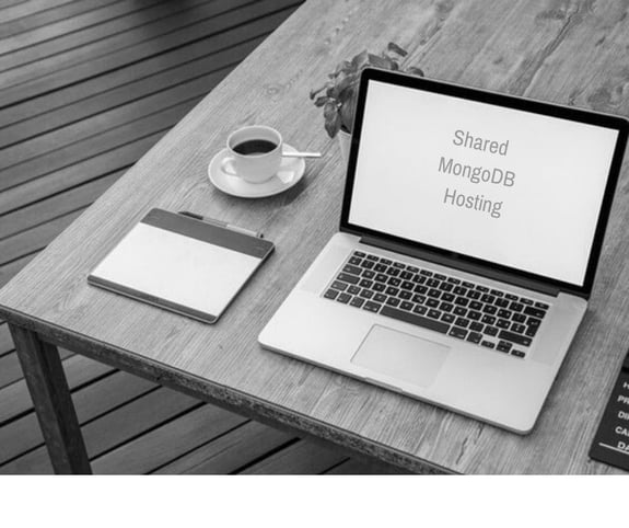 grayscale image of laptop and coffee on a wooden table, as a concept of mongodb hosting